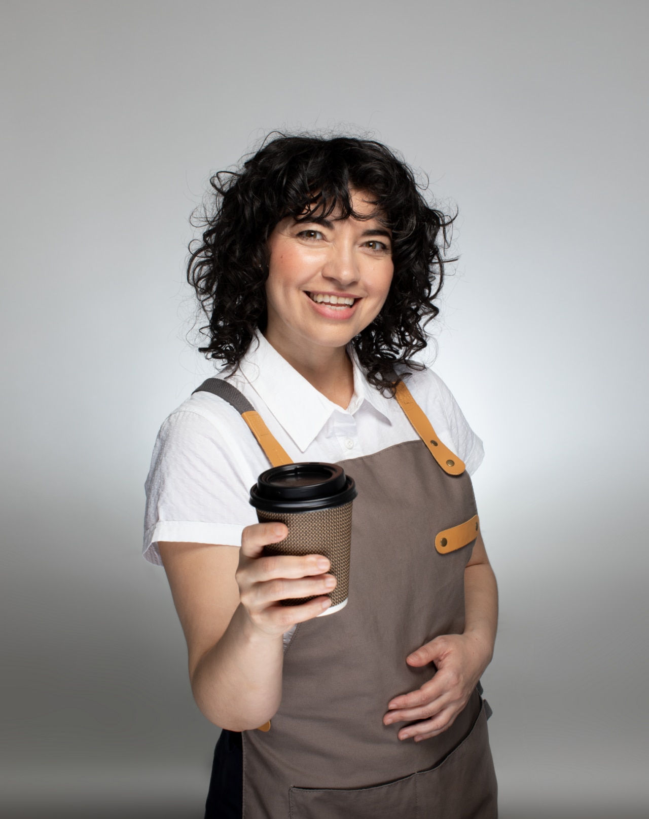 Femme barista souriante tenant une grande tasse de café dans sa main.