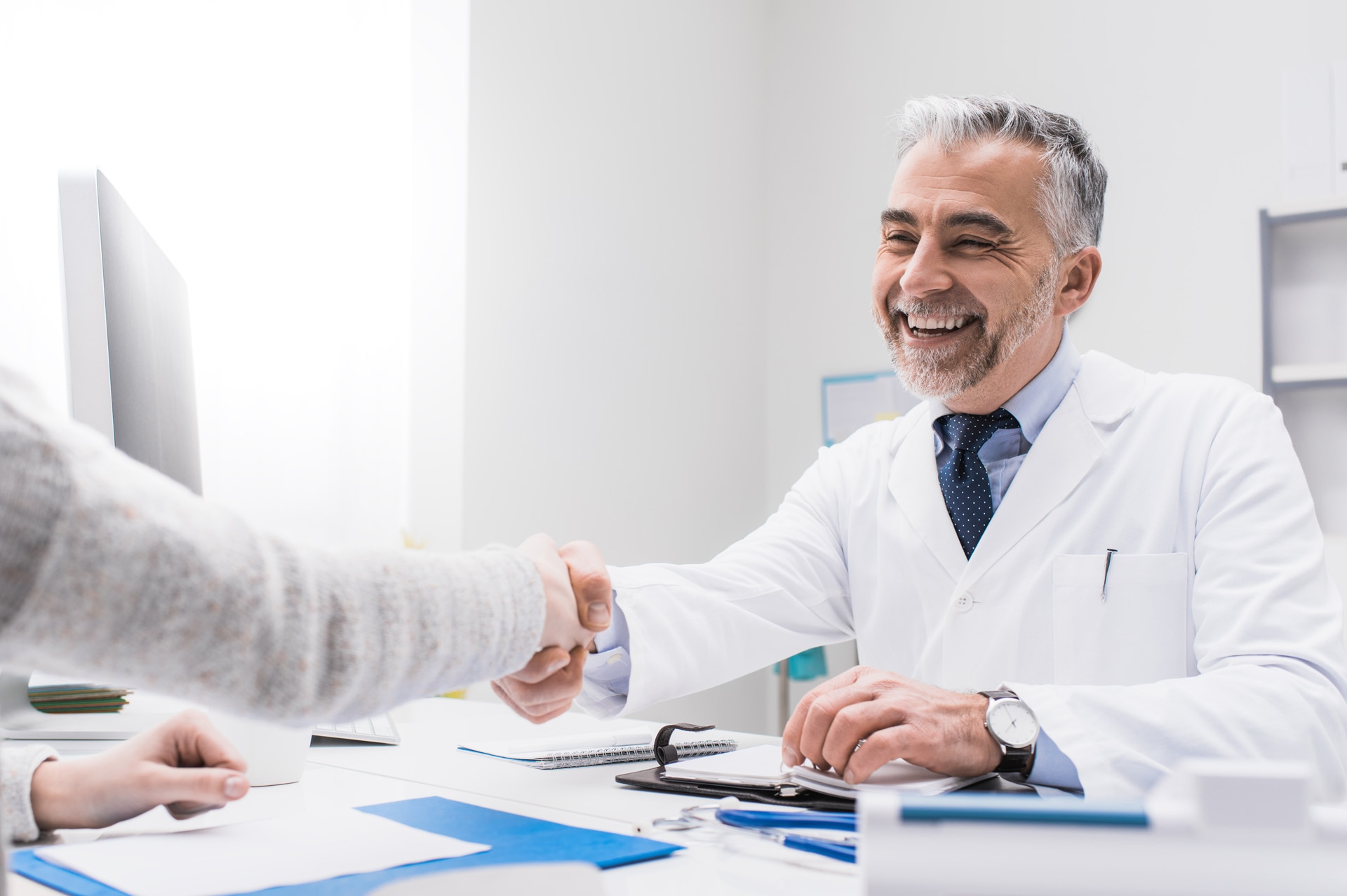 Médico sorrindo e apertando a mão de um paciente