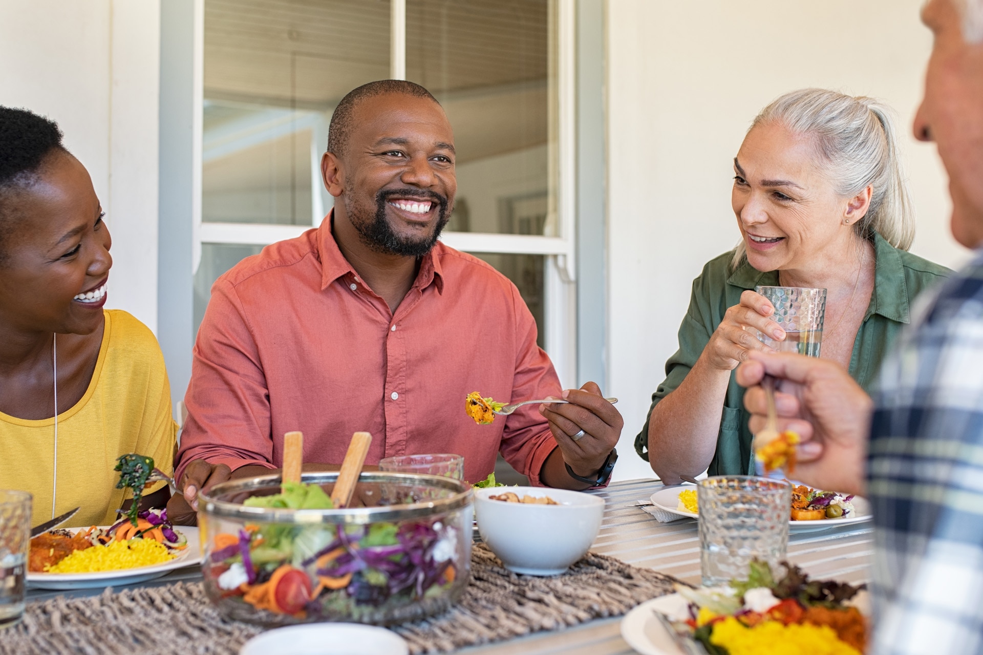 Amigos felizes aproveitando o almoço juntos em casa. 