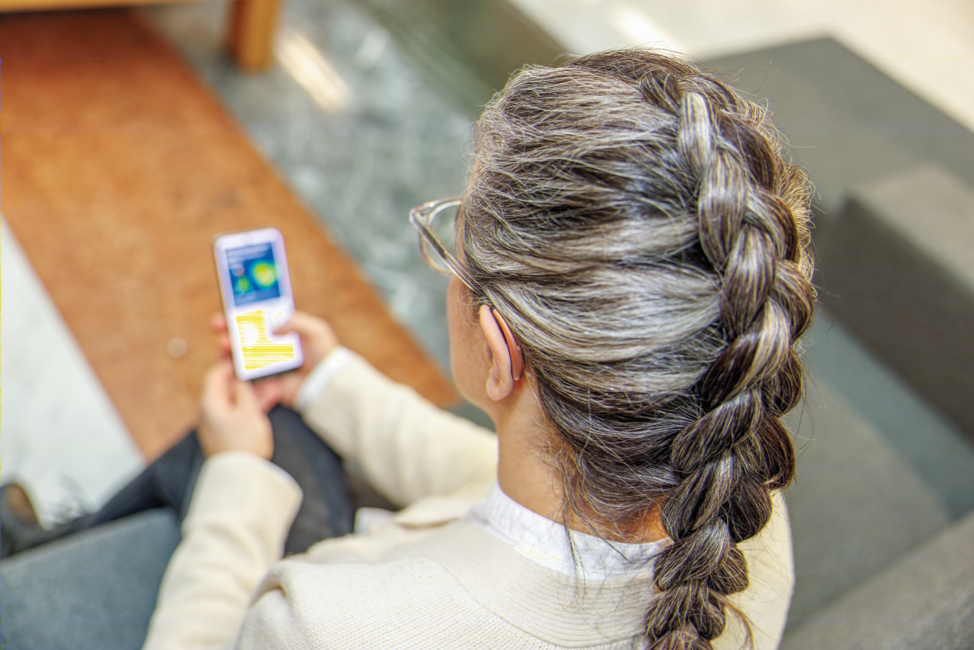 Woman wearing small hearing aid using smartphone