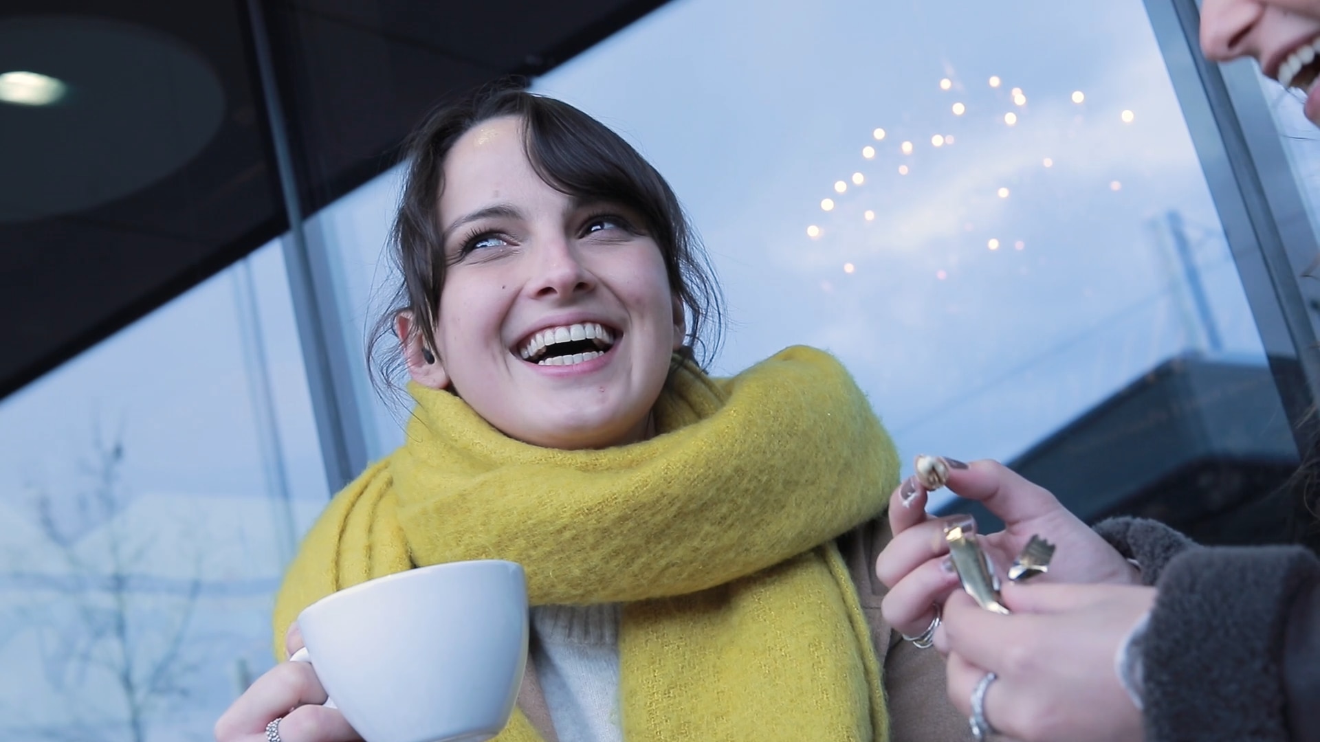 Usuária de Phonak Virto feliz durante uma conversa com a sua amiga em um café ao ar livre.