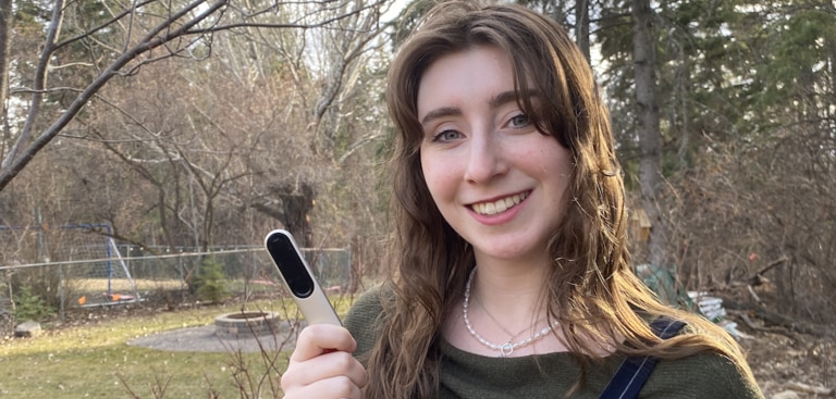 Mulher jovem segurando o seu microfone do Roger On e sorrindo – uma cena externa.