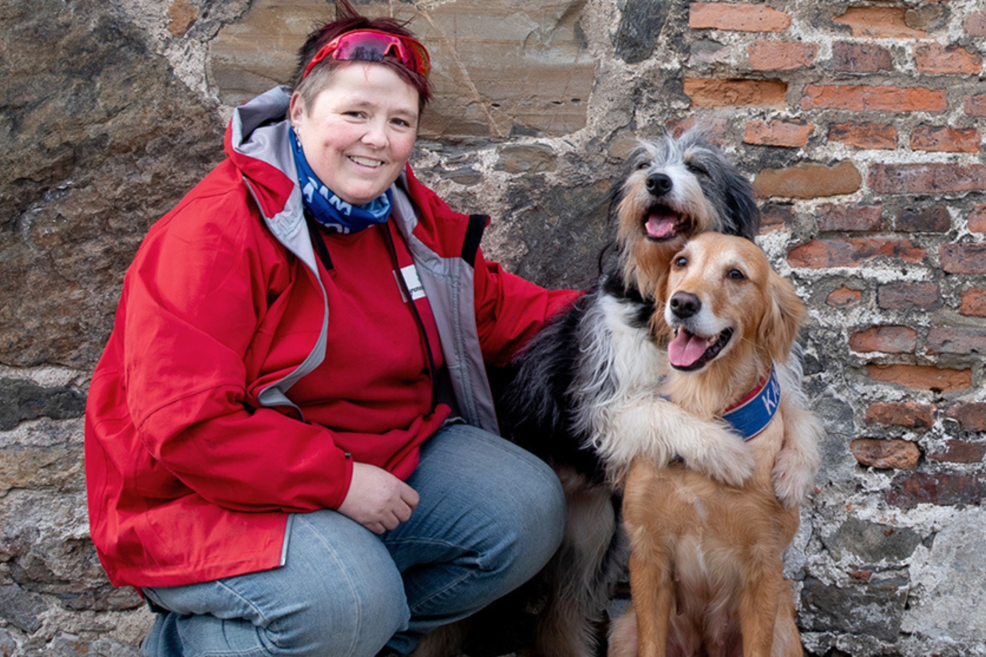 Mulher sorrindo com os seus dois cachorros.