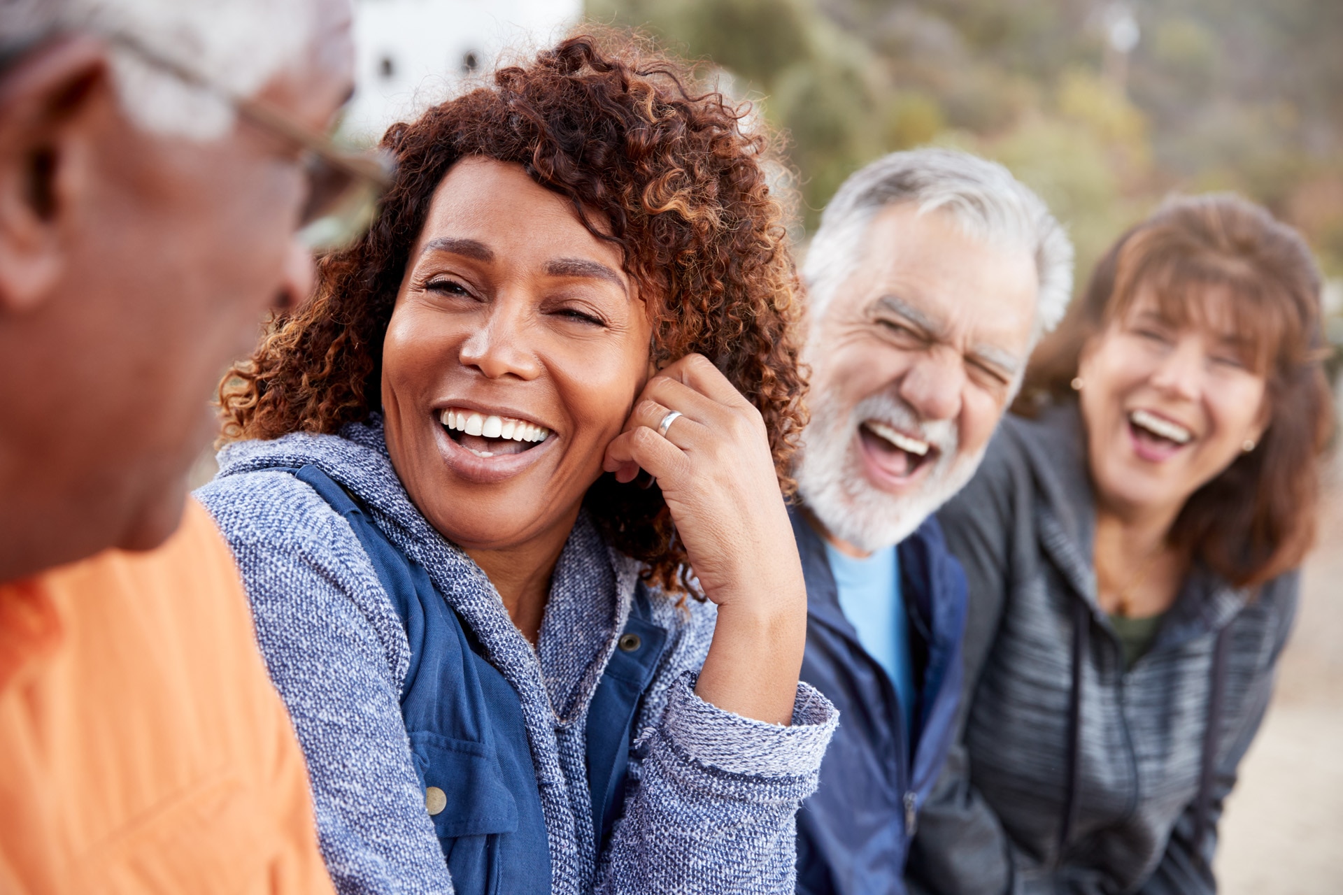 Group Of Senior Friends On Hike In Countryside Talking And Laughing Together