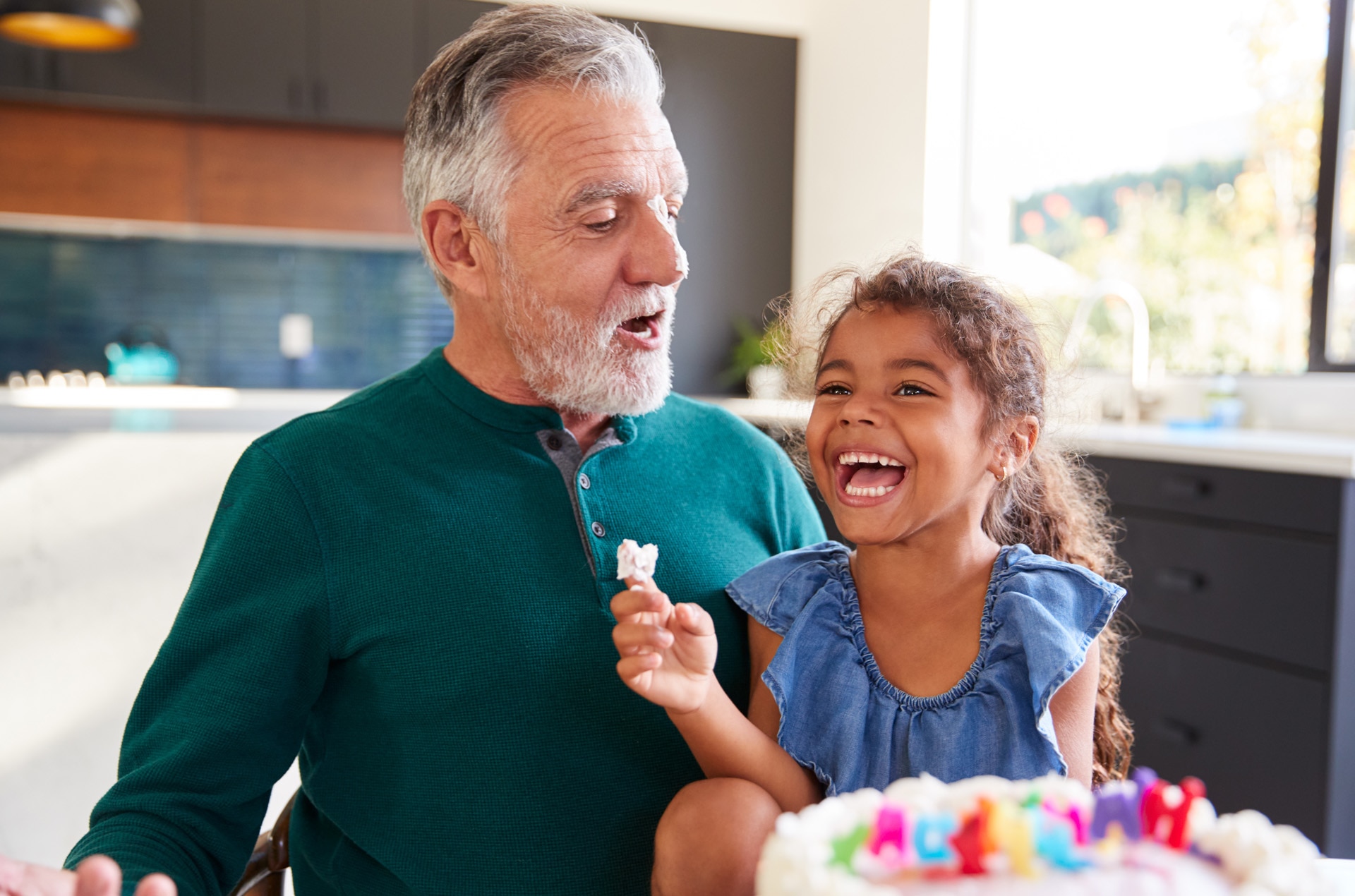 Granddaughter Celebrates Birthday With Grandfather By Putting Cake Cream On His Nose And Laughing