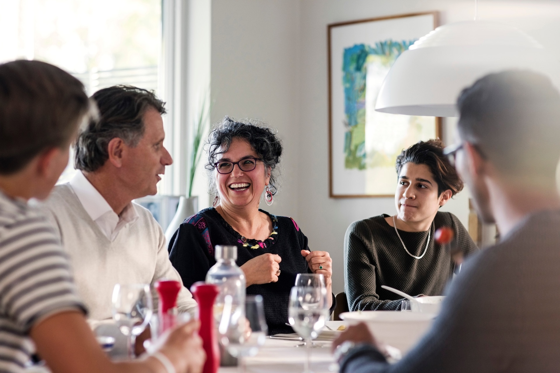 Happy friends discussing at dining table in dinner party