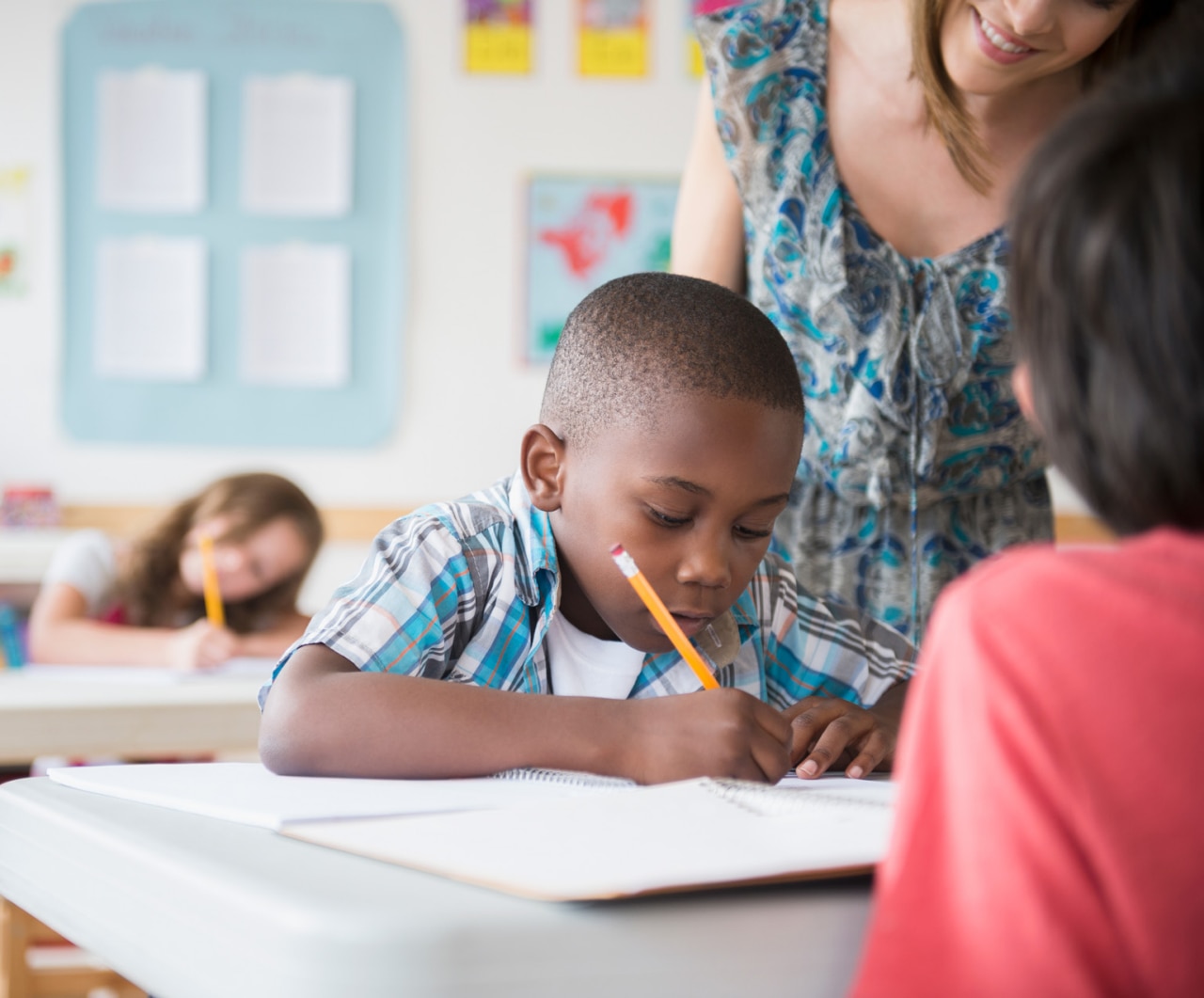 Children (8-9) with female teacher learning in classroom