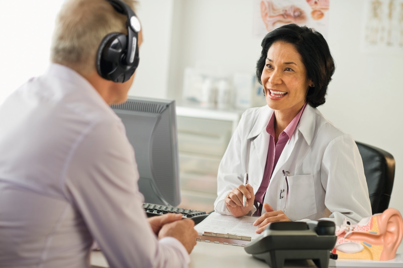 Middle-aged male's hearing check in a female audiologist's office.