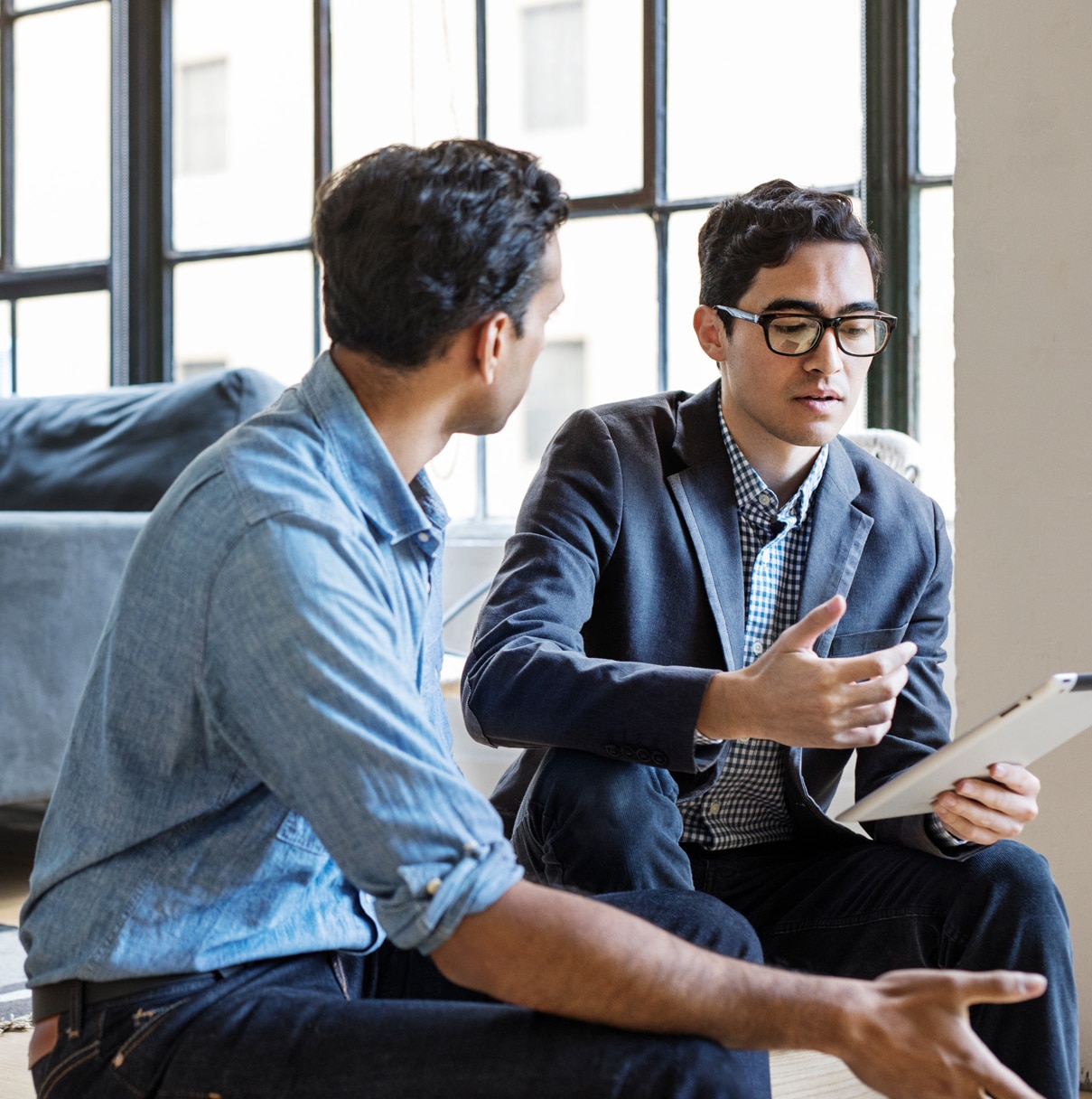 Business people discussing over digital tablet sitting in office