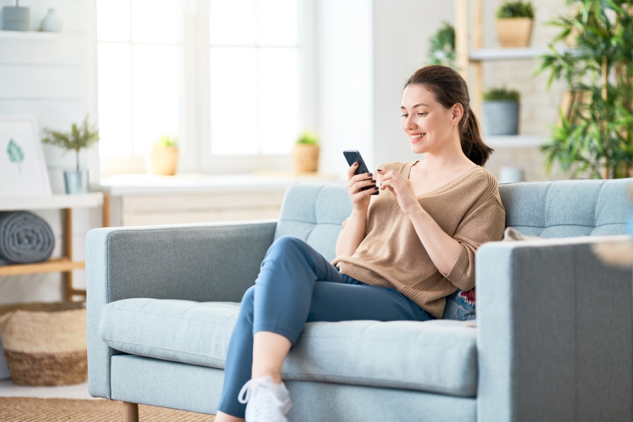 1422270389 Happy casual beautiful woman is talking on a phone sitting on a sofa at home.; Shutterstock ID 1422270389; purchase_order: -; job: -; client: -; other: -