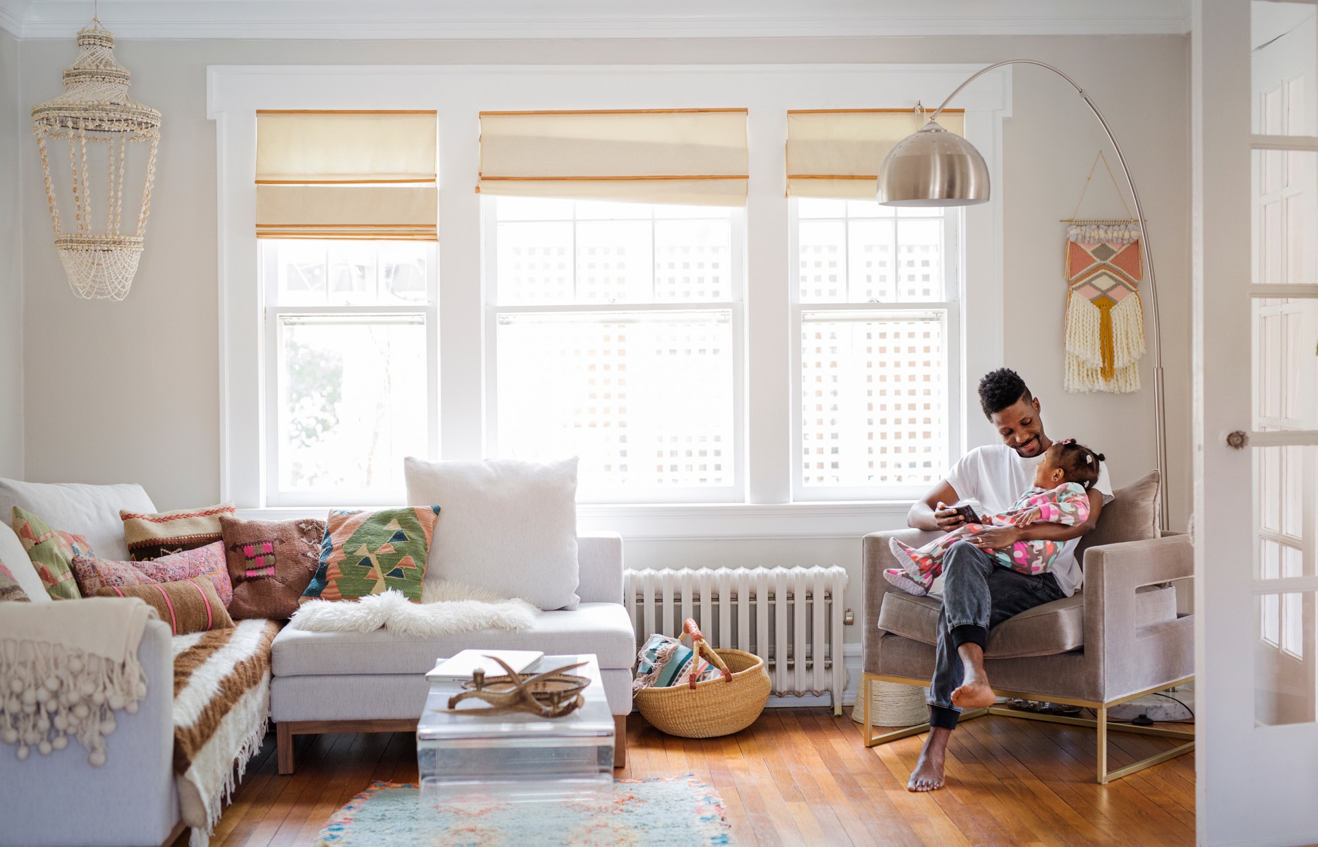Father holding daughter and playing on a tablet - domestic scene in a living room. Father holding daughter and playing on a tablet - domestic scene in a living room.