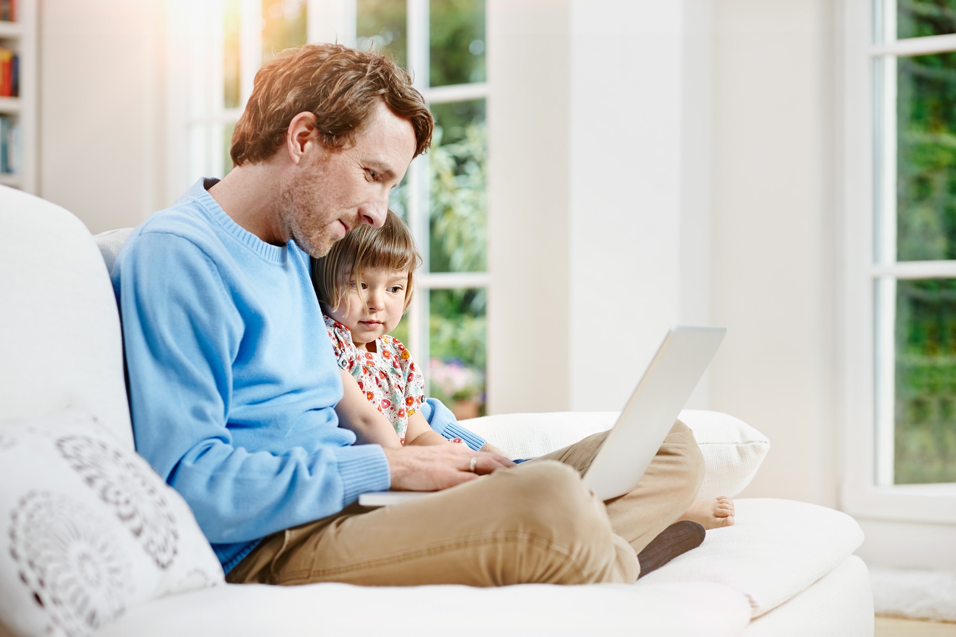 Father and daughter sitting on a sofa and using a laptop. Father and daughter using laptop