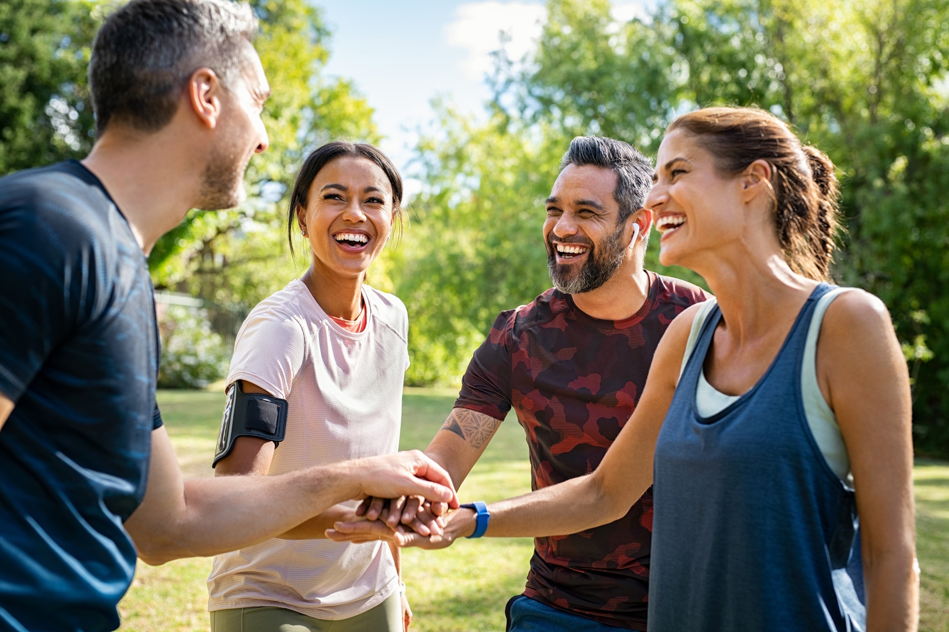 公園で笑う成熟した多種多様な人種のスポーツ愛好家たち A group of mature people doing sports in a park