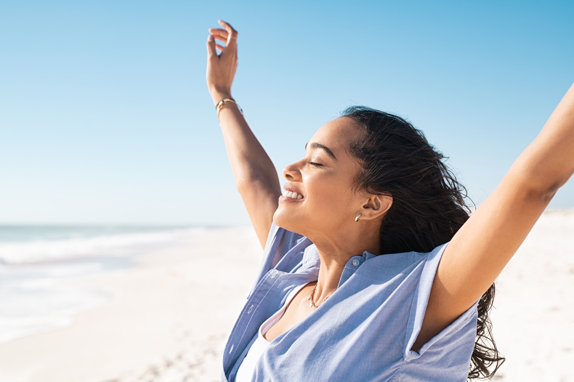 A happy hispanic woman with outstretched arms standing on a beach A happy hispanic woman with outstretched arms standing on a beach