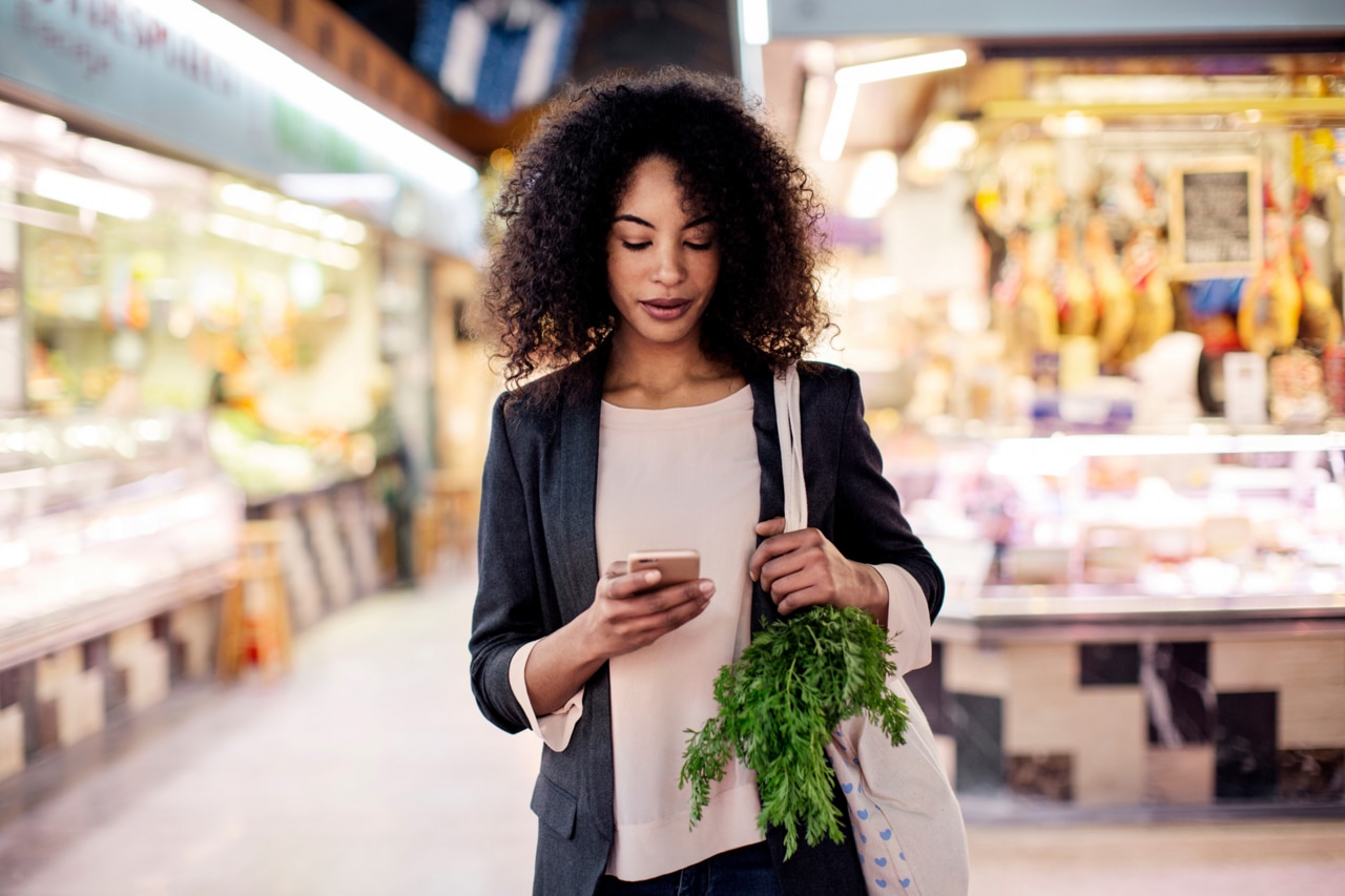 Woman using mobile phone while shopping in market